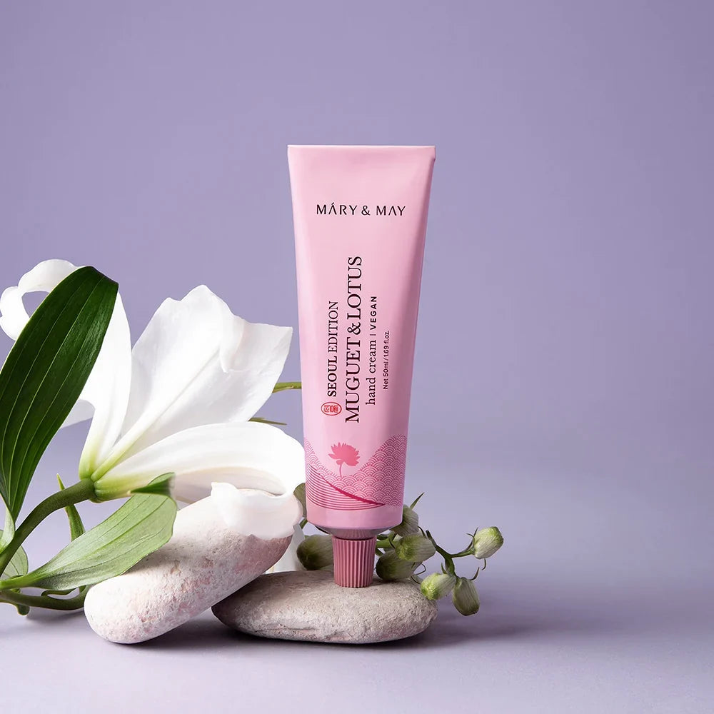 Mary&May Muguet & Lotus Hand Cream 50 ml con flores blancas en una escena lila